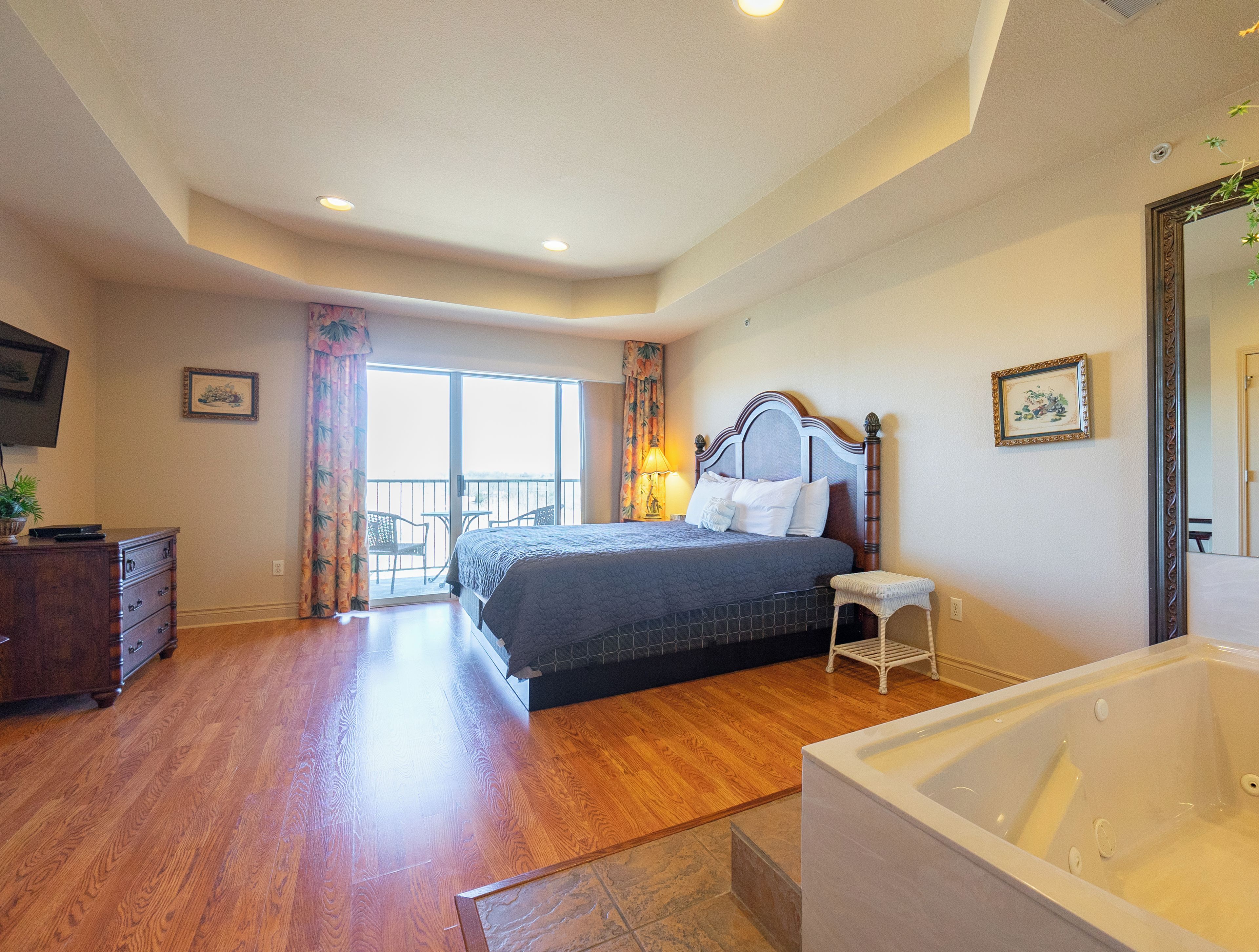 Un dormitorio con una cama grande, un baño con bañera y un balcón con vistas.