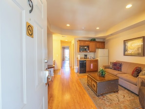 A spacious living room with a sofa, coffee table, and a kitchen area in the background.