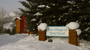 Une enseigne indiquant « The Village at Steamboat », avec des arbres couverts de neige et une montagne en arrière-plan.