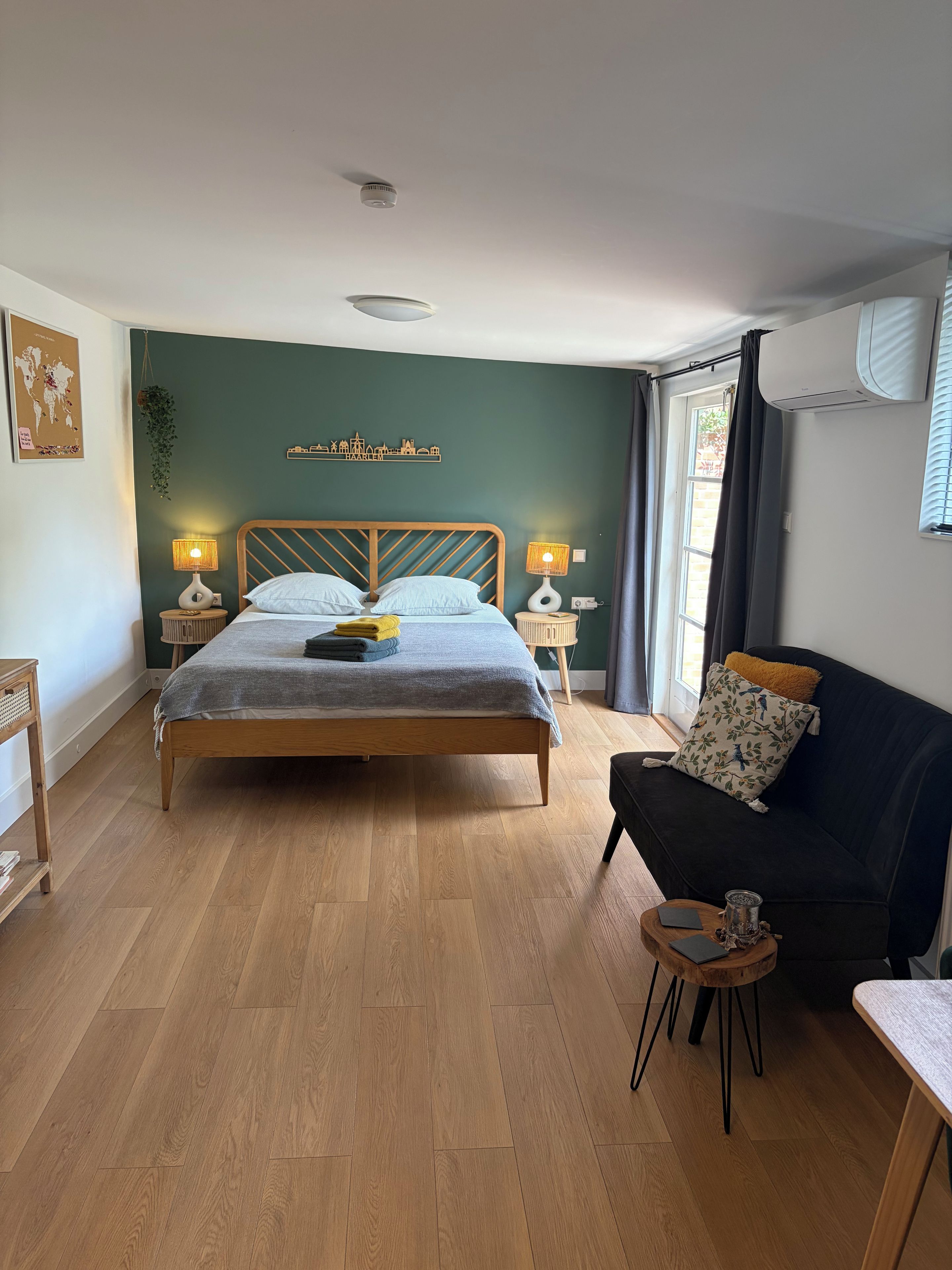 A bedroom with a bed, bedside tables, a sofa, and a small table with a lamp.