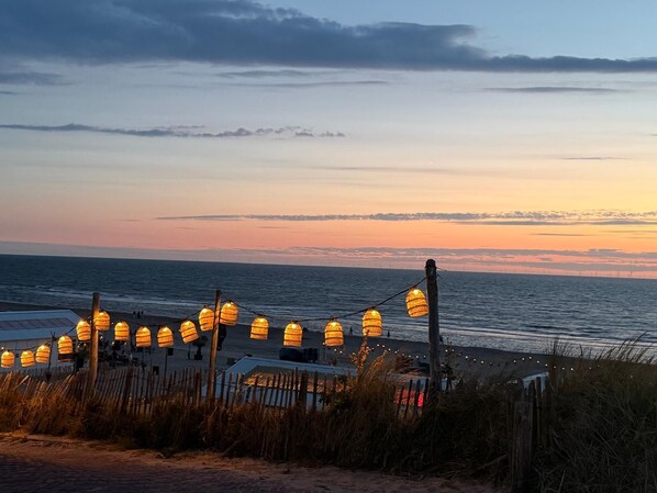 A beach view with string lights and a wooden fence.