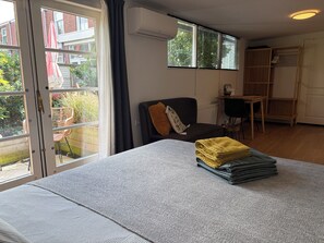 A room with a bed, a chair, a table, and a window with curtains.