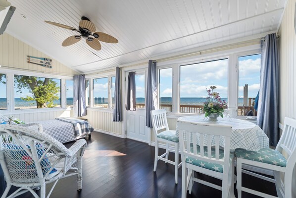 Habitació amb vista al mar, ventilador de sostre i taula amb cadires.
