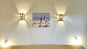 Pared con un retrato enmarco de dos personas en una playa, flanqueado por dos luces de pared con diseños de estrellas.