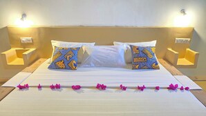 Una cama con dos almohadones decorativos, una mesita de noche y una lámpara de pared.