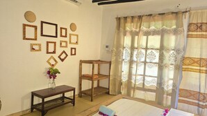 Una habitación con cama, una pequeña mesa de madera, un estante y decoración en la pared.