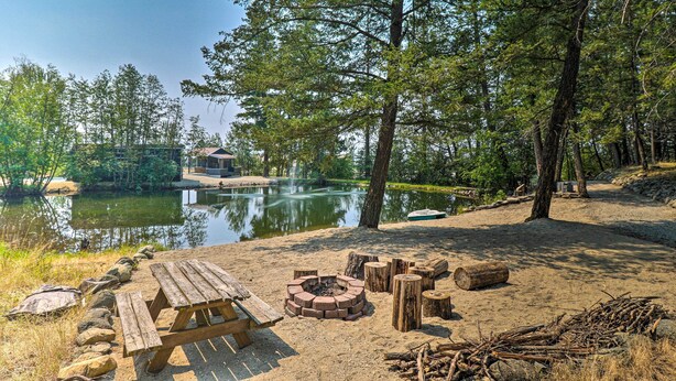 A campsite with a wooden picnic table, a fire pit, and a sandy area. - Eureka Tiny Home w/ Hot Tub & Community Beach! (Eureka)