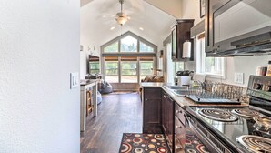 A kitchen with a large stove, a sink, and a window overlooking a deck. - Eureka Tiny Home w/ Hot Tub & Community Beach! (Eureka)