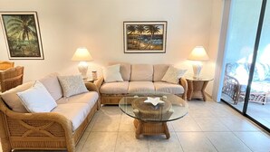 A living room with a beige sofa, two side tables with lamps, a glass coffee table, and two framed pictures on the wall. - 🌴Palms Heaven Villa•  2BR/2BA/2 Pools & Heated Hot Tubs •Near IMG / Beaches (Bradenton)