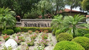 A stone sign with the name 'Shoreval' surrounded by a landscaped garden with various plants and flowers. - 🌴Palms Heaven Villa•  2BR/2BA/2 Pools & Heated Hot Tubs •Near IMG / Beaches (Bradenton)