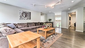 Ein modernes Wohnzimmer mit einem Ecksofa, einem Holztisch und einem großen abstrakten Gemälde an der Wand.