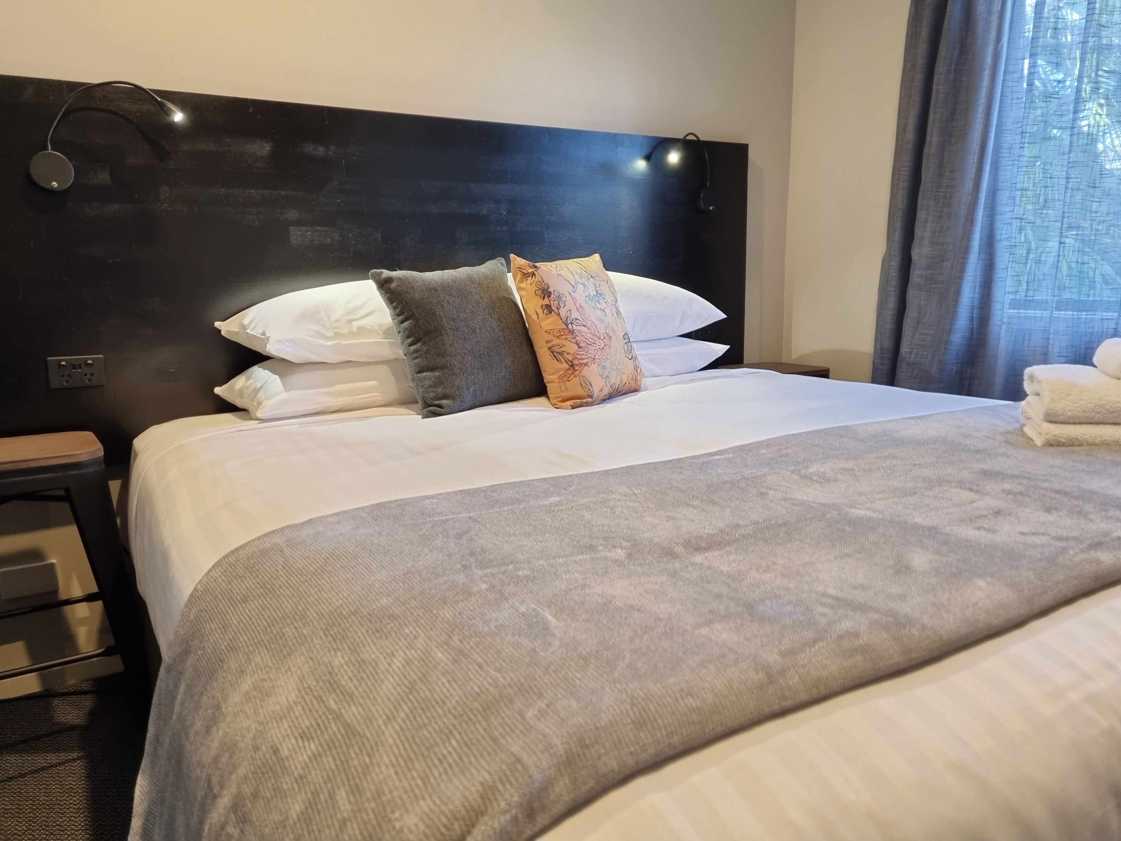 A hotel room with a large bed, a headboard, and a bedside table.