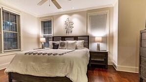 Une chambre à coucher avec un grand lit, deux tables de chevet, un ventilateur de plafond et des lampes fixées au mur.