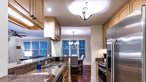 Une cuisine moderne dotée de plans de travail en granit, d’appareils électroménagers en acier inoxydable et d’armoires en bois.
