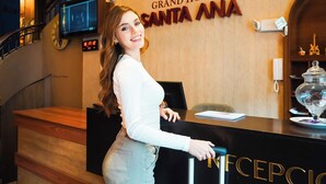 Un mostrador de recepción en el Grand Hotel Santa Ana con un reloj, una pantalla digital y una barra de recepción.