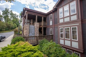 A two-story building with a balcony, stone pillar, and multiple windows.