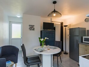 A modern kitchen with a refrigerator, microwave, and a dining area with a round table and chairs.