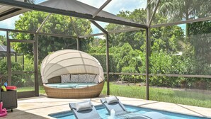 Un espace piscine intérieure avec des chaises longues et un jacuzzi, le tout abrité sous une pergola.