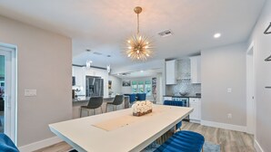 Une cuisine moderne avec des meubles blancs, un îlot central et un lustre.