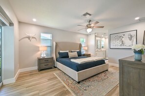 A bedroom with a bed, nightstands, a ceiling fan, a large window, and a wall-mounted artwork. - Beautiful Naples Retreat  (Naples)