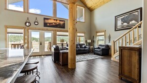 A spacious living area with a large wooden dining table, leather sofas, and a staircase. - The Yellowstone Hideaway - Beautiful 3 Bedroom, 2 Bath Cabin- Sleeps 10 (Island Park)