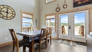 A dining area with a wooden table and chairs, large windows, and a view of the outdoors. - The Yellowstone Hideaway - Beautiful 3 Bedroom, 2 Bath Cabin- Sleeps 10 (Island Park)