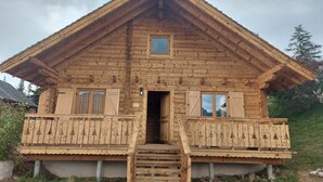 Une cabane en bois dotée d’un balcon, d’un escalier menant à l’entrée et d’une petite fenêtre située au-dessus de la porte.