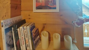 Un intérieur en bois avec une étagère où sont posés des livres, des bougies et une télécommande.