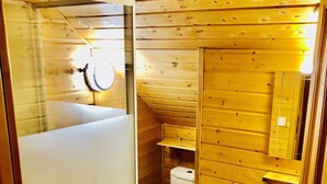 Une salle de bain rustique, avec des murs en bois, une douche en verre, des toilettes et un lavabo.