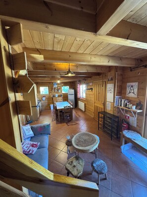 Interior de uma cabana de madeira com sala de jantar, cozinha e área de estar.