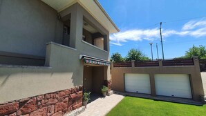 A modern two-story house with a stone base, a covered entryway, and a garage. - Holiday apartment newly renovated with air conditioning (Siófok)