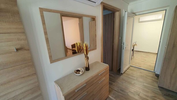 A modern bedroom with a wooden dresser, a large mirror, and a vase with dried plants. - Holiday apartment newly renovated with air conditioning (Siófok)