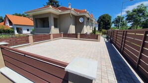 A building with a tiled patio area, a fenced deck, and a satellite dish.