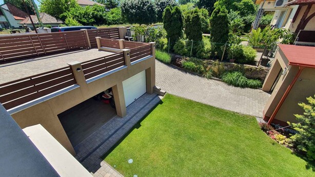 A residential property with a covered outdoor area, a paved driveway, and a well-maintained lawn.