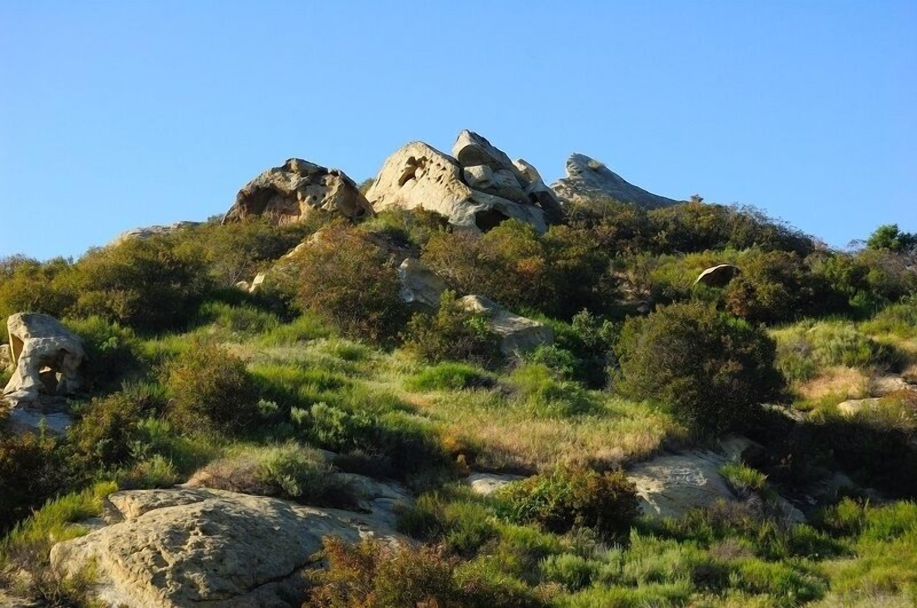 Ein felsiger Hang mit vereinzelten Steinen und vereinzelter Vegetation.