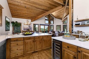 A spacious kitchen with wooden cabinets, a large island, and a dining area with a view of the outdoors.