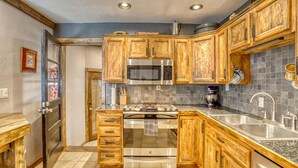 Una cocina con armarios de madera, electrodomésticos de acero inoxidable y salpicadero de azulejos.
