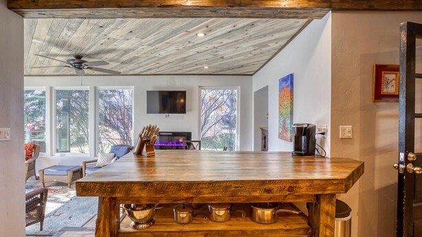Un amplio salón con techo de madera, una mesa grande de madera y una chimenea.
