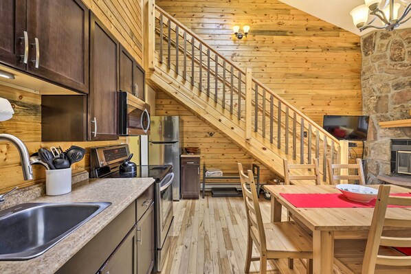 Enjoy a warm and inviting cabin-style kitchen and dining area with a wooden table, wooden cabinets, and a granite countertop.