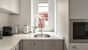 A modern kitchen with a built-in oven, a sink, and a window with a view of a red building. - Elegant Luxury Old Town Studio-apt by Lisbeyond (Lisboa)