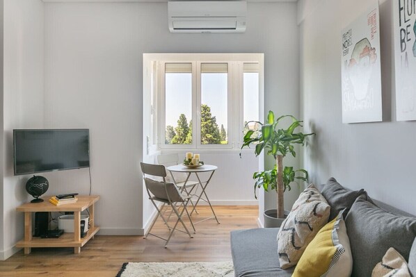Relax in a spacious living room with a large flat-screen TV, comfortable sofa, and a dining area with a view of the outdoors.