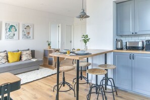 Relax in this stylish living and dining area, featuring a sofa, dining table, and kitchenette.