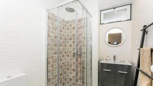 A bathroom with a glass shower enclosure, a sink with a mirror above it, and a towel rack. - Lively 2 Bedroom Apartment in Iconic Alfama by Lisbeyond (Lisboa)