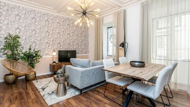A modern living room with a sofa, dining table, and a TV. - Lively 2 Bedroom Apartment in Iconic Alfama by Lisbeyond (Lisboa)