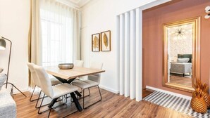 A modern hotel room with a wooden dining table, beige chairs, a large mirror, and a pineapple decoration. - Lively 2 Bedroom Apartment in Iconic Alfama by Lisbeyond (Lisboa)