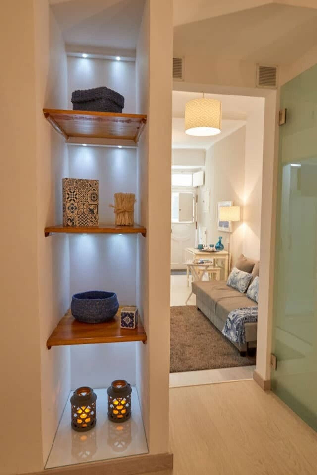 Um corredor estreito com uma estante de madeira exibindo objetos decorativos.