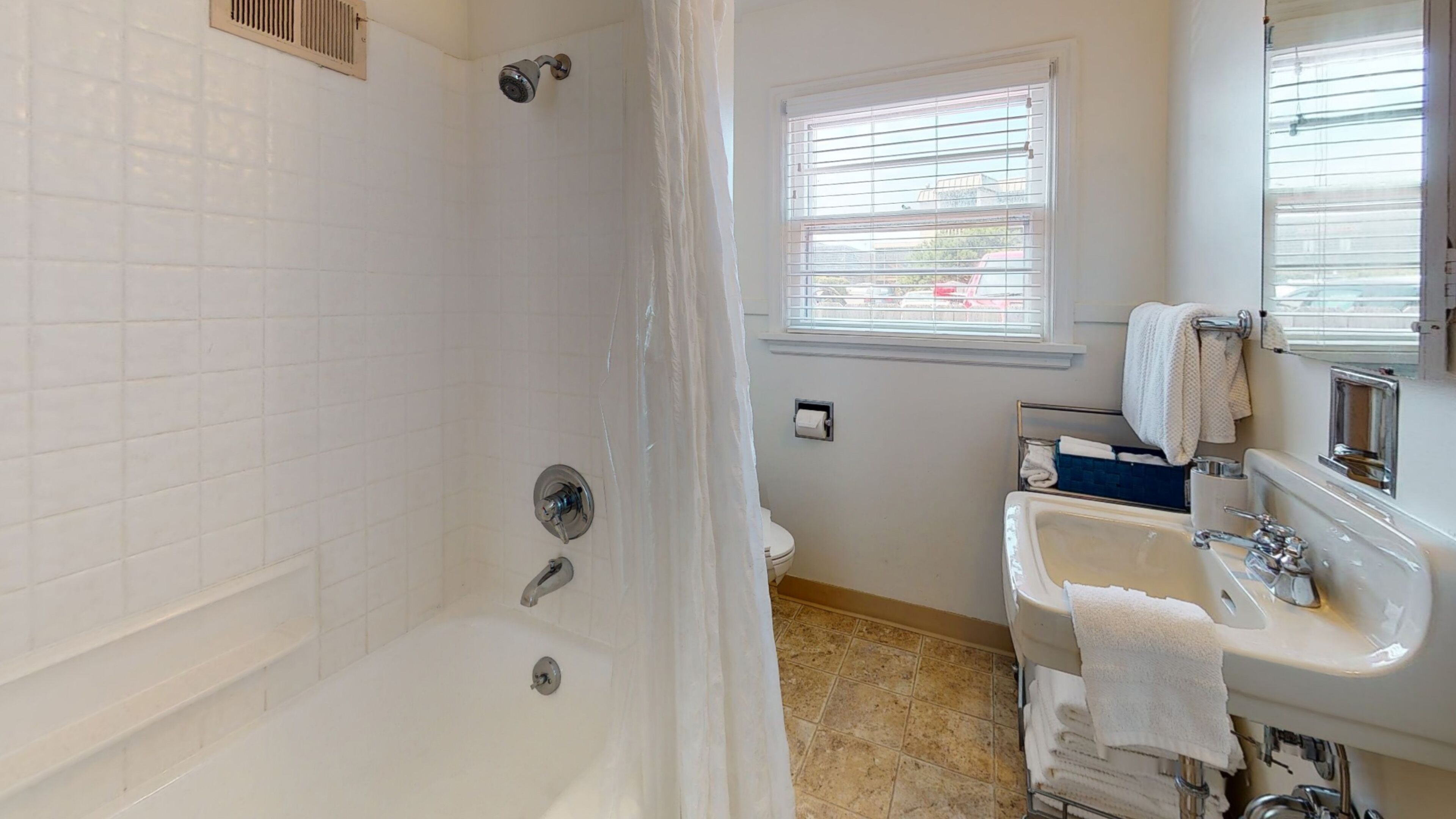 A bathroom with a shower, toilet, sink, and window.