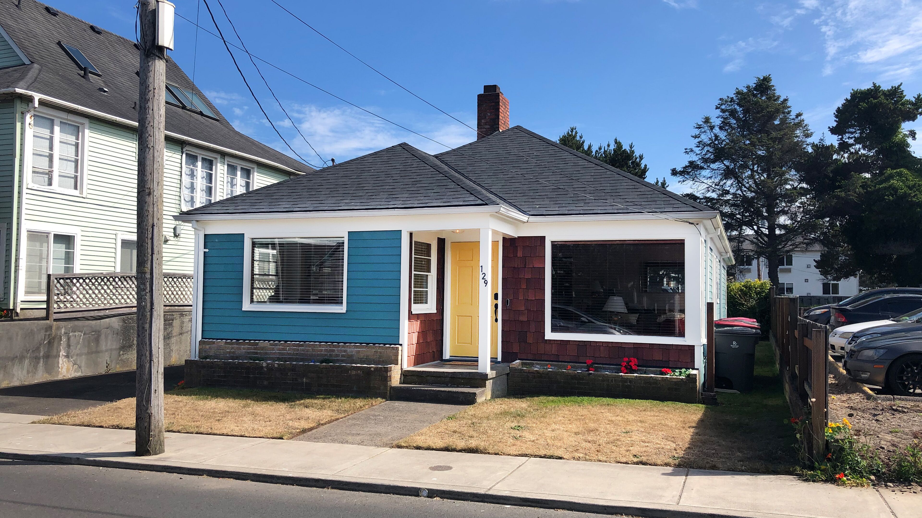 A single-story house with a gabled roof, a front porch, and a visible number '129' on the door.