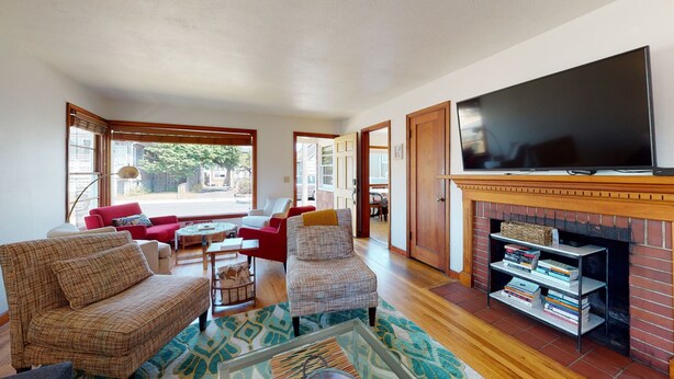 A spacious living room with a fireplace, a flat-screen TV, and a bookshelf.
