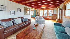 Een gezellige woonkamer met een bruine leren bank, een teal fauteuil en een houten salontafel.